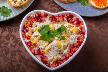 Salad with chicken and pineapples in a heart-shaped salad bowl next to tartlets