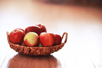 Wicker basket with fresh ripe red apples on wooden background. Harvesting. Autumn. September