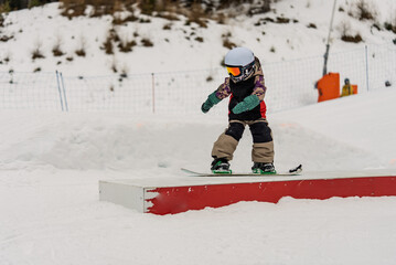Children in snowpark in Dolomites Alps. Snow park box tricks. Snowboarder in park on a box. Winter...
