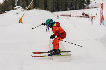 Children skiers in snowpark in Dolomites Alps. Snow park box tricks. Skiers in park on a box. Winter jibbing in snwopark. Ski lessons on snowpark. Children learn to ski with an instructor.