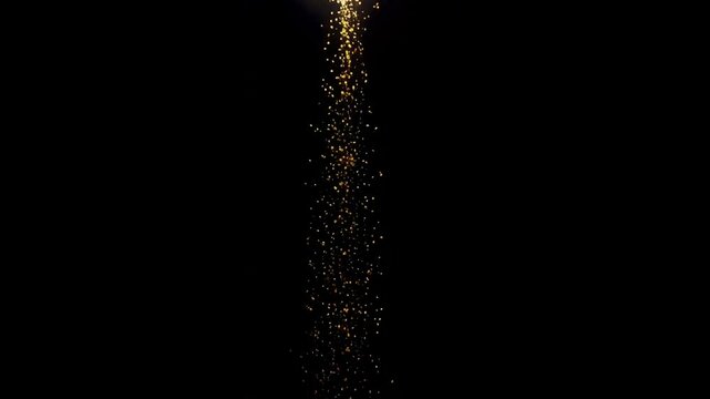 Glittering golden particles falling on a dark background