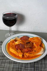 A traditional Alentejan tomato soup served with a glass of local red wine on a rustic restaurant table, capturing the essence of authentic Portuguese cuisine.