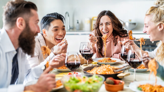 Happy friends having vegan pasta dinner party at home - Multiracial people drinking red wine at lunch break - Food and beverage concept with guys and girls dining together Italian food - Powered by Adobe