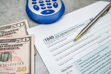 US 1040 form or US Individual income pen calculator dollar on desk. Accounting documents taxation