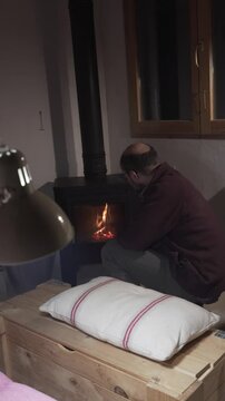 man in his forties lighting the cooker fire in an idyllic rustic space with an evening atmosphere