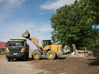 Construction Site with Loader Dumping Debris into Truck under Blue Sky