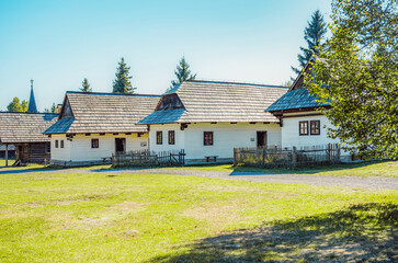 Obraz premium Rare wooden bell tower with folk houses located in open-air museum of Liptov Village, Slovakia - Pribylina