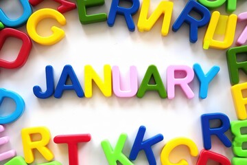 Fototapeta premium Colorful magnetic letters spelling January surrounded by other alphabet letters.