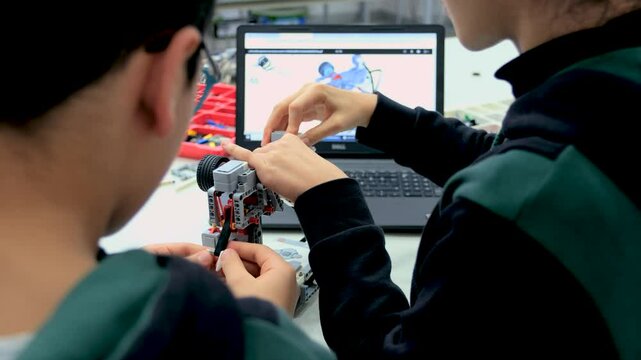 Elementary School Robotics Classroom: Diverse Group of Brilliant Children with Enthusiastic Teacher. Creative kids working on the tech project at school.