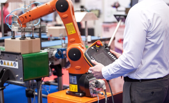 Engineer operating advanced robotic arm in an automated industrial environment for efficient box handling and packing