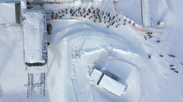 Aerial view of a queue of people waiting for a chairlift at a snowy ski slope in a winter resort