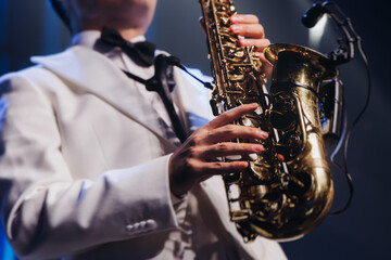 Fototapeta premium Concert view of saxophonist musician, saxophone sax player with vocalist and musical band during jazz orchestra show performing music on a stage in the scene lights, concert in a musical club hall