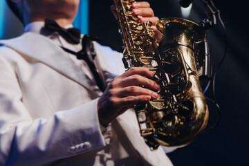 Obraz premium Concert view of saxophonist musician, saxophone sax player with vocalist and musical band during jazz orchestra show performing music on a stage in the scene lights, concert in a musical club hall