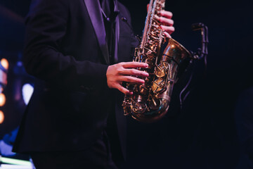 Concert view of saxophonist musician, saxophone sax player with vocalist and musical band during jazz orchestra show performing music on a stage in the scene lights, concert in a musical club hall