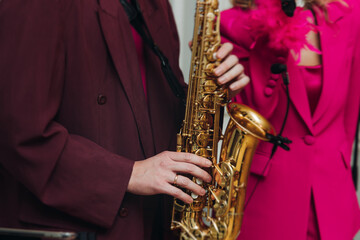 Obraz premium Concert view of saxophonist musician, saxophone sax player with vocalist and musical band during jazz orchestra show performing music on a stage in the scene lights, concert in a musical club hall