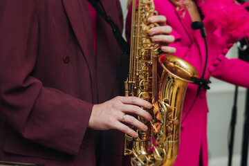 Naklejka premium Concert view of saxophonist musician, saxophone sax player with vocalist and musical band during jazz orchestra show performing music on a stage in the scene lights, concert in a musical club hall