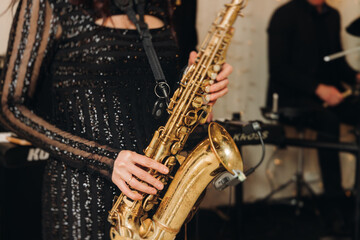 Naklejka premium Concert view of female saxophonist musician, saxophone sax player woman with vocalist and musical band during jazz orchestra show, performing music on a scene in the stage lights in a musical club