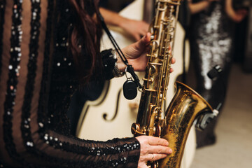 Obraz premium Concert view of female saxophonist musician, saxophone sax player woman with vocalist and musical band during jazz orchestra show, performing music on a scene in the stage lights in a musical club