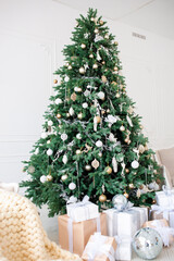 Elegant Christmas interior with a decorated tree in gold and white, wrapped gifts, a vintage beige sofa, and an armchair with a cozy knit blanket. Bright white walls create a festive, minimalism