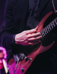 Concert view of an electric guitar player with vocalist and rock band performing in a club, male...