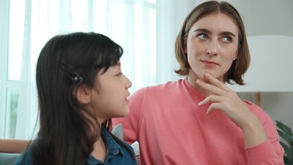 Happy mother sharing experience with daughter while sitting in living room. Caucasian mom and happy child talking and spend time together. Attractive girl listen parent story while smiling. Pedagogy.