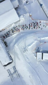 Aerial view of a queue of people waiting for a chairlift at a snowy ski slope in a winter resort
