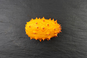 Kiwano on black plate, jelly melon, cucumis metuliferus ripe fruit, orange spiked horned melon