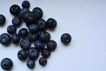 Fresh bilberries spread on white table close up top view macro. A lot of blue berries on white surface.