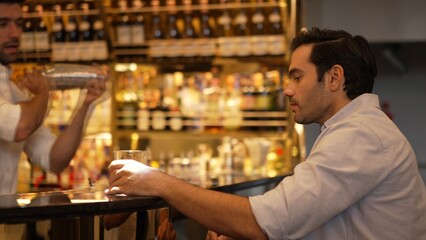 Profile closeup of smiling smart man in white shirt drinking cocktail in Old fashioned of special party beverage vibrant at nightclub on Friday meeting night time at luxurious counter bar. Vinosity.