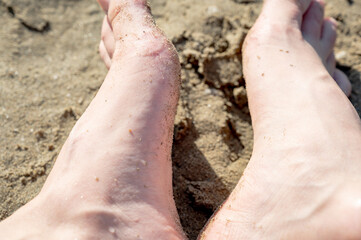 Women's feet on the sand. Legs, feet on a sandy beach near the sea. Leisure and sports.