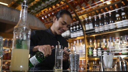 Asian bartender pouring mixed cocktail juice liqueur all ingredient into sliver shaker alcohol drink, making special advertisement creative tasty, focused refreshing showcase at bar luxury. Vinosity.