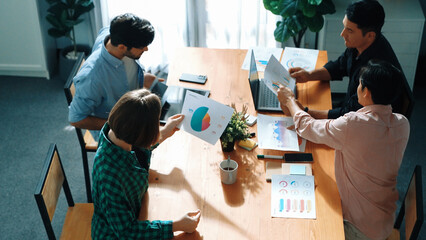 Top view of business people discuss idea while marketing team joining meeting. Manager pointing financial graph while colleagues talking to investor by using phone and brainstorm idea. Convocation.