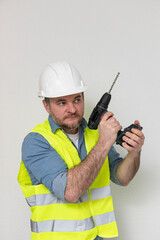 A construction worker wearing a white helmet and yellow vest holds a drill in a dynamic pose, expressing readiness, symbolizing skill and professionalism in construction tasks. free space