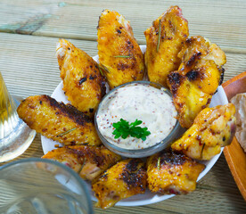 Plate of beer snack - roasted chicken wings with mustard sauce and herbs