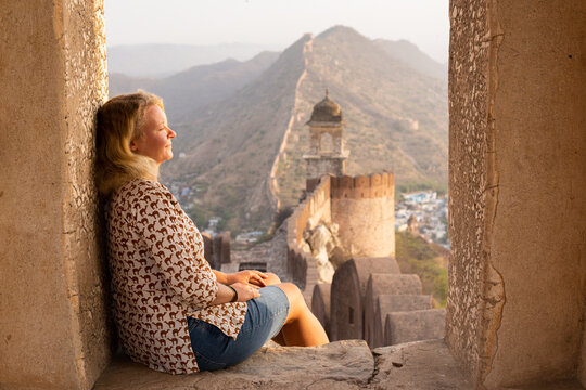 Young blonde woman enjoying sunrise on the city walls of Jaipur in Rajasthan, India