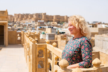 Young blonde European woman travelling in Rajasthan, enjoying panoramic view of Jaisalmer city fort, India