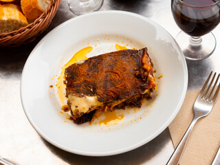 Close-up of freshly baked piece of lasagna bolognegse on white ceramic plate