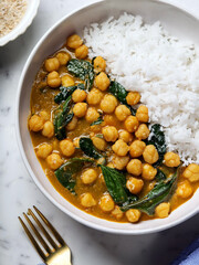 Creamy chickpea curry with spinach accompanied by a serving of rice makes for a meatless and...