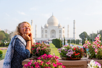 Attractive young woman enjoying the iconic view over the marble white Taj Mahal mausoleum in Agra, Uttar Pradesh, India