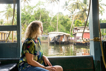 European tourist having a traditional straw houseboat ride on the backwaters of Kerala, India