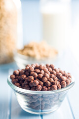 Breakfast cereal chocolate balls in bowl on blue table.