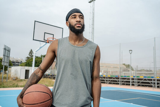 Young basketball player holding ball and waiting on court