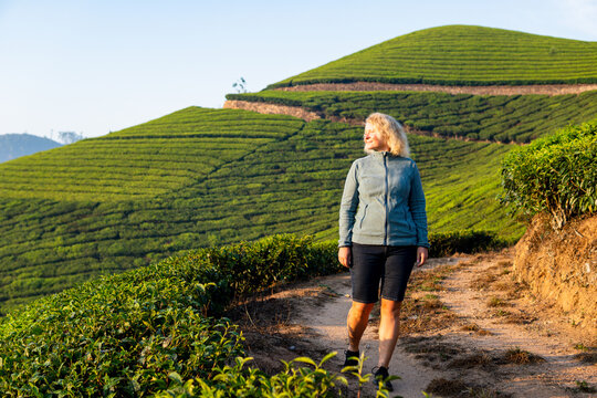 Young blonde woman hiking among tea plantations in Munnar, Kerala, India