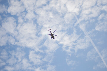 The helicopter in the sky. Flying Vehicle. A helicopter flies against the background of light clouds.