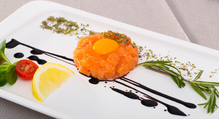 Salmon 200 g, balsamic, greens, black pepper, olive oil, lemon. Finely chop the salmon, season with oil, pepper, salt and lemon juice. Garnish with yolk and balsamic