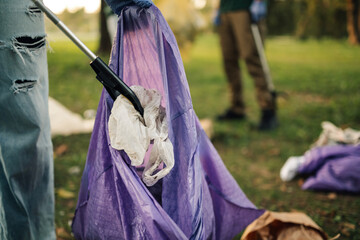 Volunteer picking up trash with grabber tool in public park