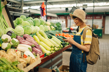 Asian woman choosing fresh vegetables at a local market stall