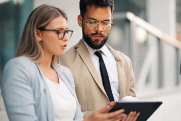 Business people having informal meeting discussing using digital tablet outdoors