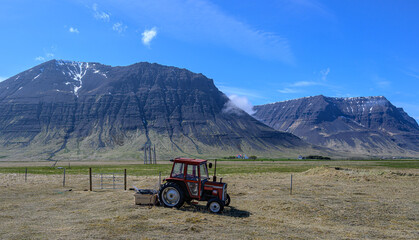 Red Tractor Sitting in Front of Mountains in Iceland 