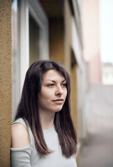 Thoughtful young woman standing near a textured wall on a quiet urban street